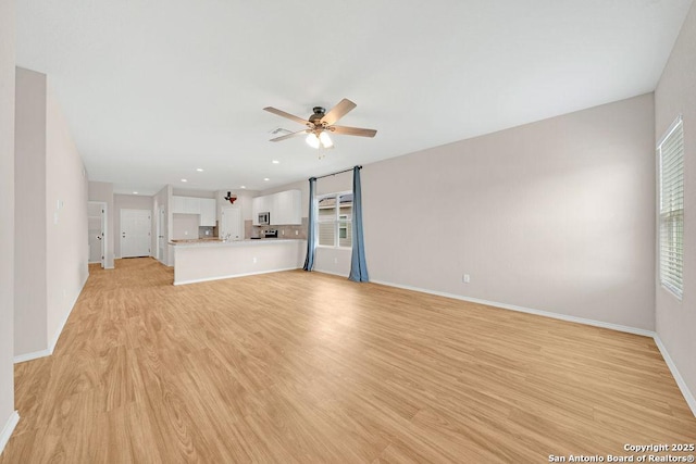 unfurnished living room featuring baseboards, a ceiling fan, light wood-type flooring, a sink, and recessed lighting