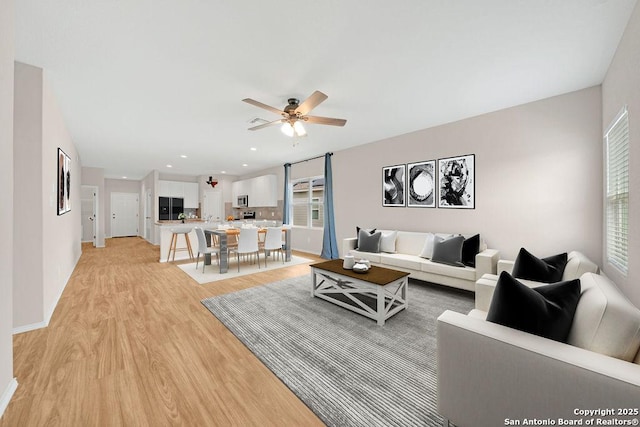 living area featuring ceiling fan, light wood finished floors, recessed lighting, and a healthy amount of sunlight