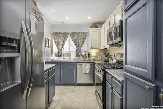 kitchen with appliances with stainless steel finishes, ornamental molding, a sink, stone counters, and backsplash