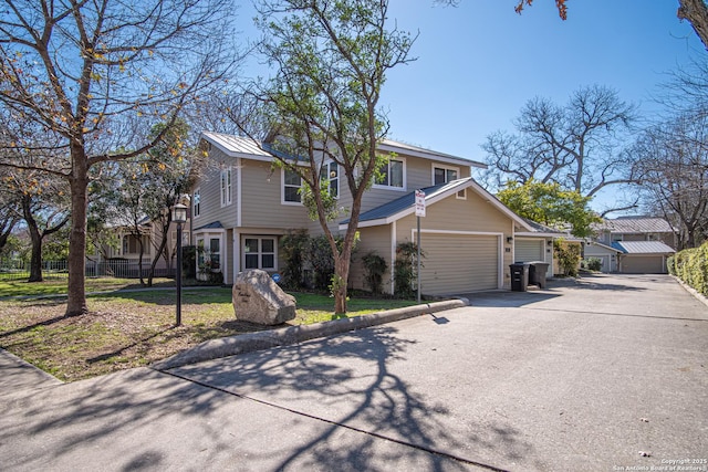 view of front of home featuring a garage, driveway, metal roof, and fence