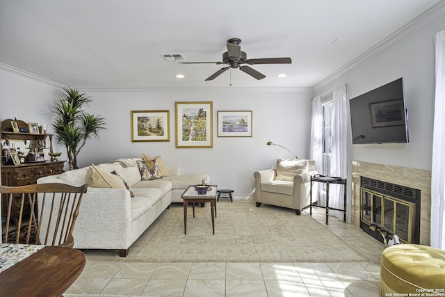 living room featuring visible vents, a ceiling fan, crown molding, a fireplace, and light tile patterned flooring