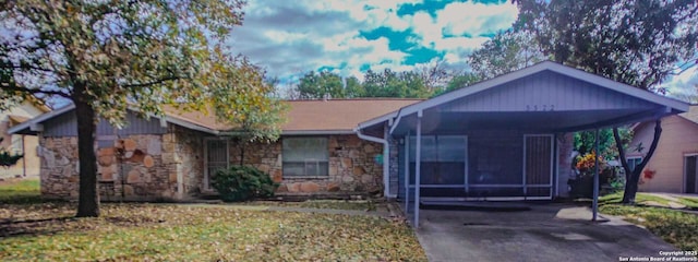 view of front facade featuring a carport, stone siding, and driveway