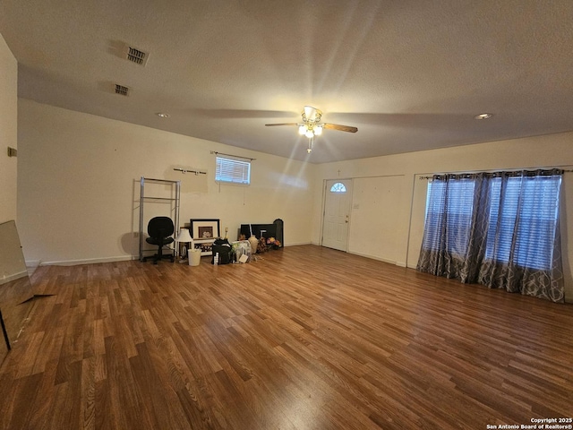 interior space with a textured ceiling, wood finished floors, a ceiling fan, and baseboards