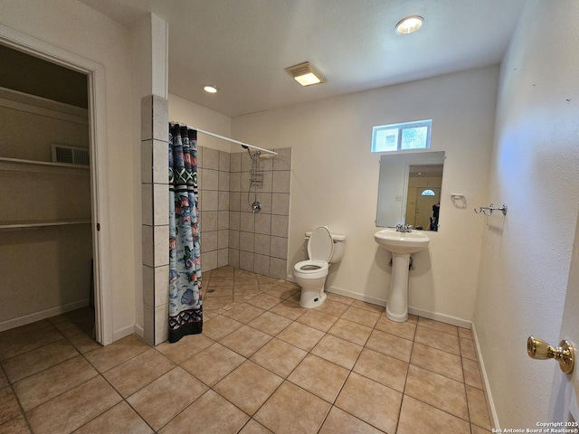 full bathroom featuring visible vents, toilet, a tile shower, tile patterned flooring, and baseboards