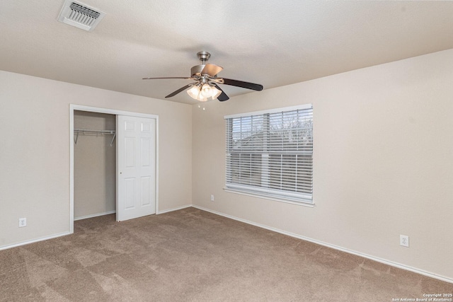 unfurnished bedroom with carpet, a textured ceiling, visible vents, and a closet