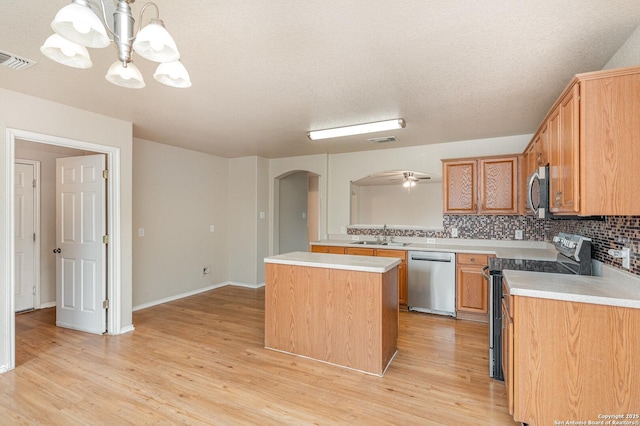 kitchen featuring appliances with stainless steel finishes, arched walkways, light countertops, and visible vents