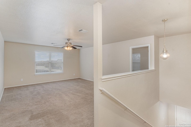 unfurnished room with visible vents, carpet flooring, ceiling fan, a textured ceiling, and baseboards