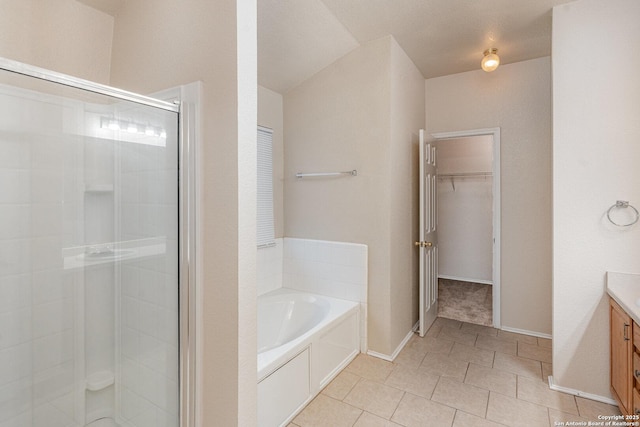 full bathroom featuring a garden tub, tile patterned flooring, vanity, a shower stall, and a walk in closet