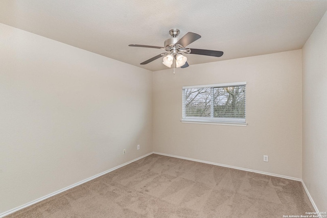 empty room featuring light carpet, ceiling fan, a textured ceiling, and baseboards