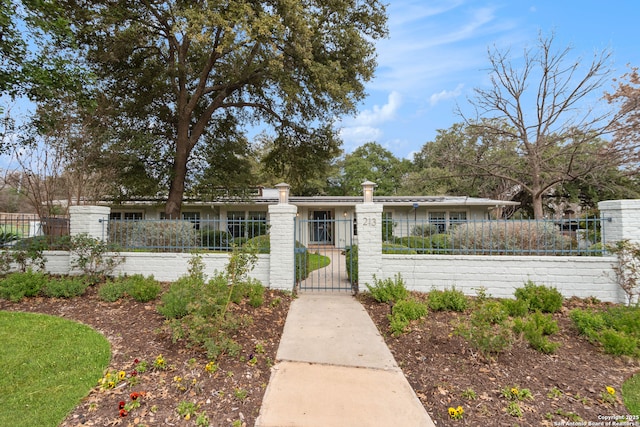 ranch-style house with a fenced front yard and a gate