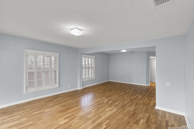 spare room with baseboards, visible vents, and wood finished floors