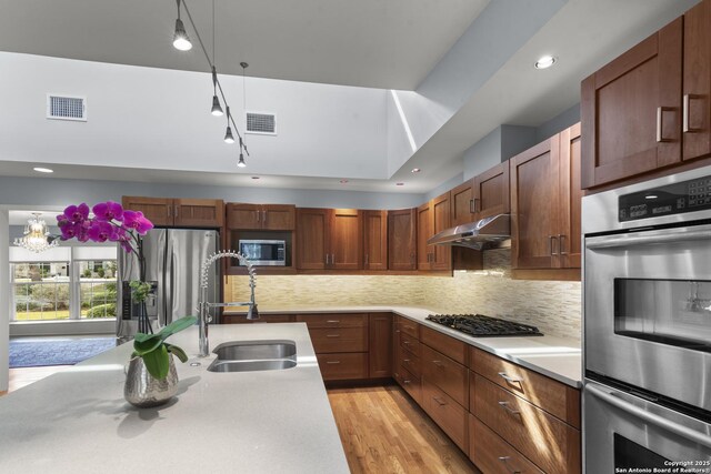 kitchen with under cabinet range hood, stainless steel appliances, a sink, visible vents, and light countertops