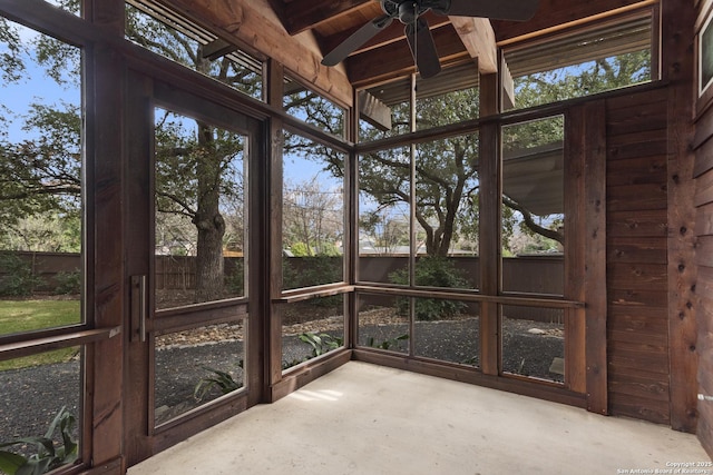 unfurnished sunroom with a ceiling fan and beamed ceiling