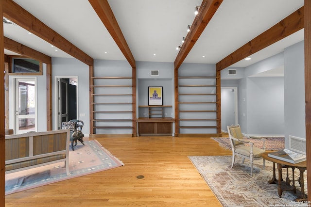 sitting room with visible vents, beam ceiling, and wood finished floors