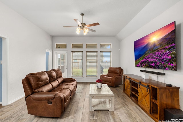 living area with baseboards, a ceiling fan, vaulted ceiling, and wood finished floors