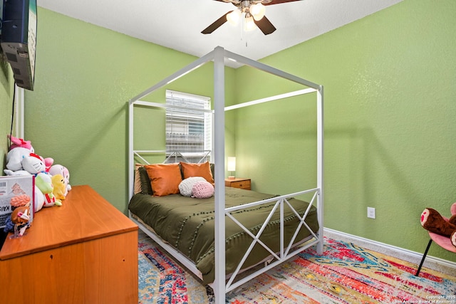 bedroom with ceiling fan, baseboards, and a textured wall