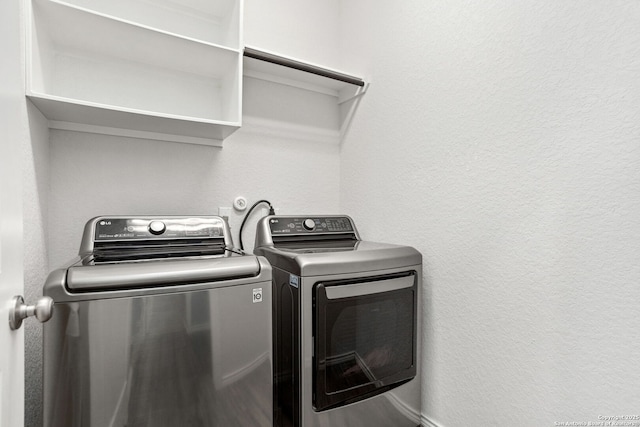 washroom featuring laundry area, a textured wall, and washing machine and clothes dryer