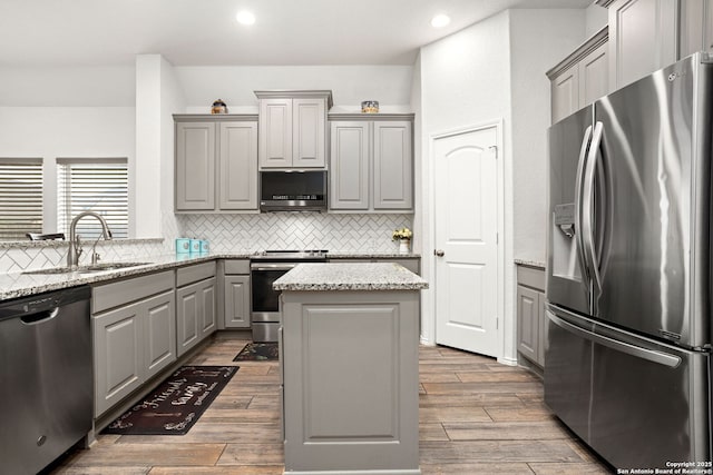 kitchen featuring stainless steel appliances, wood finish floors, a sink, and gray cabinetry