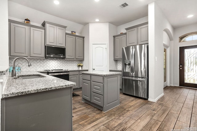 kitchen with wood finish floors, stainless steel appliances, visible vents, gray cabinetry, and a sink