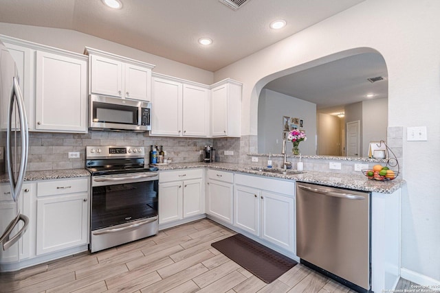 kitchen with visible vents, backsplash, appliances with stainless steel finishes, white cabinets, and a sink