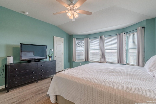 bedroom with vaulted ceiling, ceiling fan, multiple windows, and wood finished floors