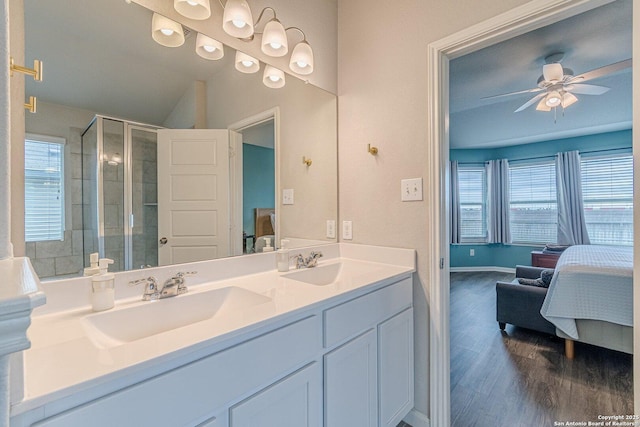 ensuite bathroom with a stall shower, ceiling fan, a sink, ensuite bath, and wood finished floors