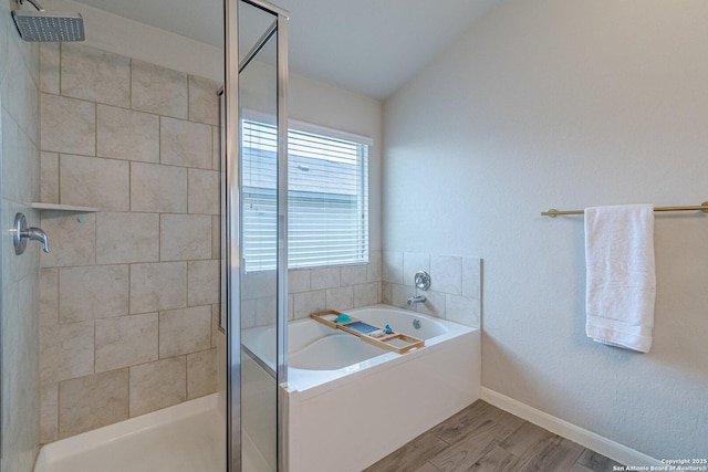 full bath with a stall shower, baseboards, wood finished floors, a garden tub, and vaulted ceiling