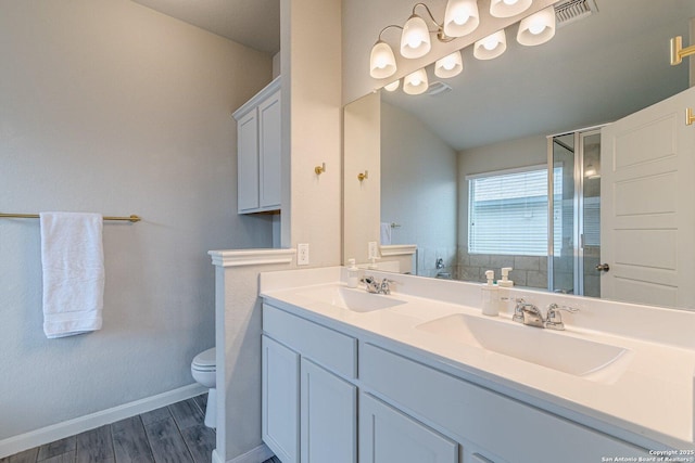 bathroom with toilet, wood finished floors, a sink, and visible vents