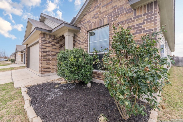 doorway to property featuring concrete driveway, brick siding, and an attached garage