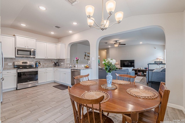 dining area featuring vaulted ceiling, visible vents, arched walkways, and a ceiling fan