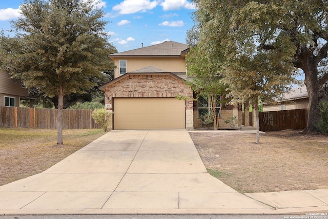 traditional-style home featuring brick siding, stucco siding, an attached garage, fence, and driveway