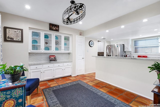 interior space with stainless steel refrigerator with ice dispenser, recessed lighting, decorative backsplash, glass insert cabinets, and white cabinets