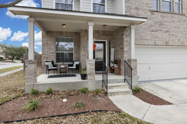 view of exterior entry with a garage, a porch, and brick siding