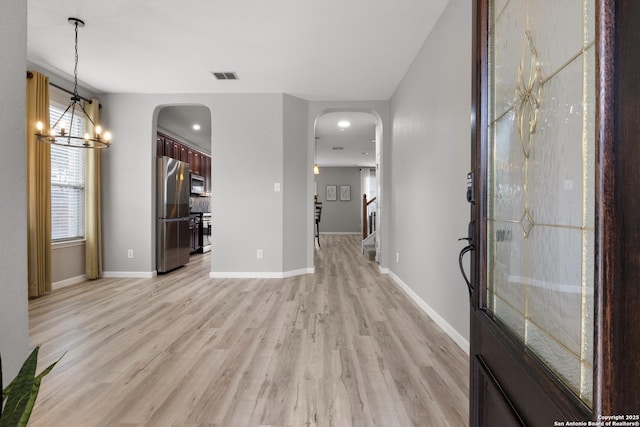 interior space with arched walkways, visible vents, baseboards, stairs, and light wood-type flooring