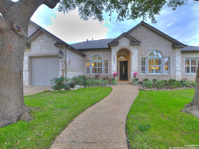 view of front facade with a garage, brick siding, a shingled roof, and a front lawn