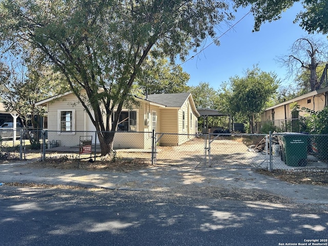 view of front of property featuring driveway, a carport, a fenced front yard, and a gate