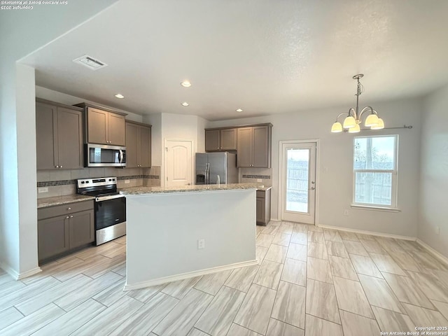 kitchen featuring tasteful backsplash, visible vents, appliances with stainless steel finishes, and pendant lighting