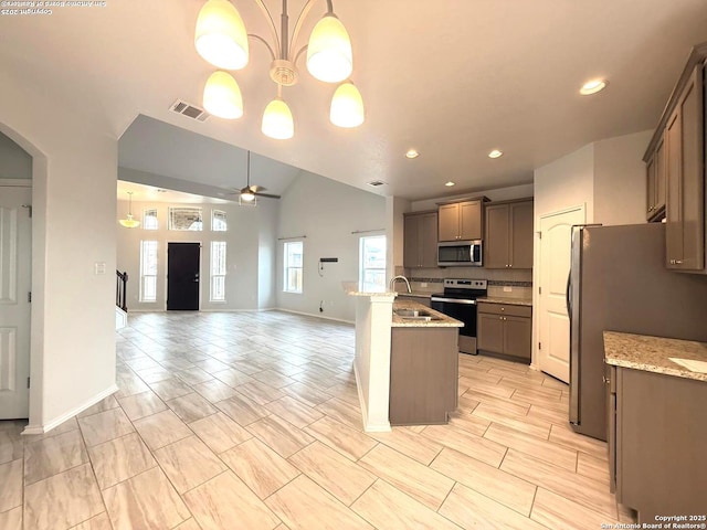 kitchen featuring arched walkways, a sink, visible vents, open floor plan, and appliances with stainless steel finishes