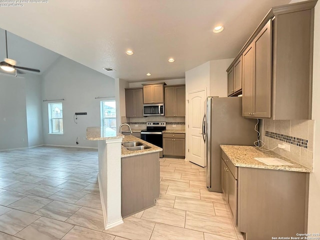 kitchen featuring appliances with stainless steel finishes, lofted ceiling, a sink, and light stone countertops