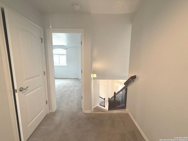 hall with carpet floors, an upstairs landing, and baseboards