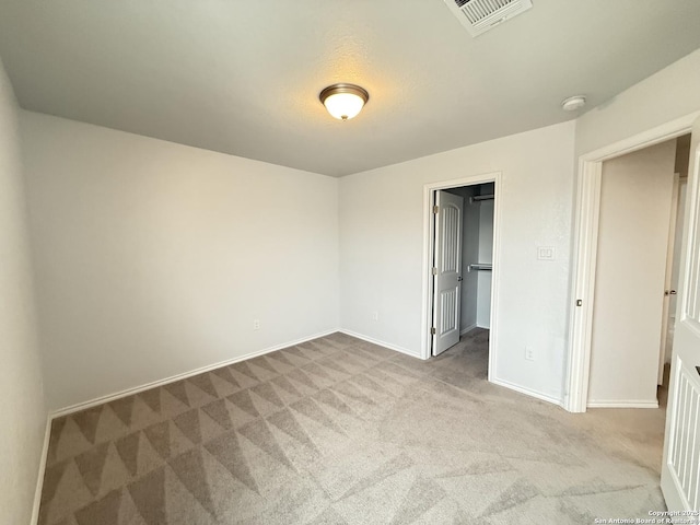 unfurnished bedroom with a walk in closet, a closet, visible vents, carpet flooring, and baseboards