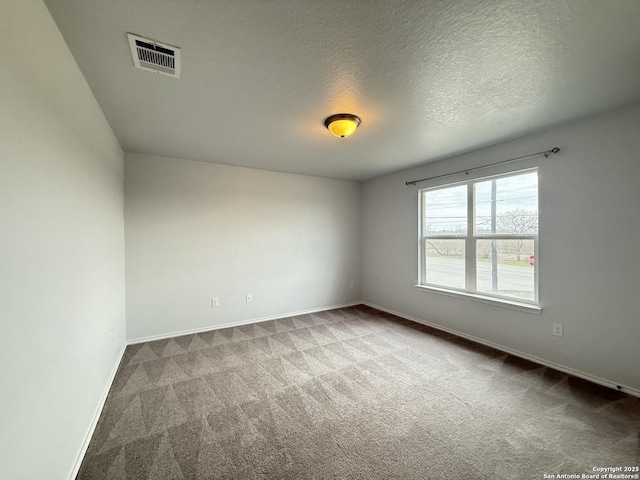 spare room with a textured ceiling, carpet, visible vents, and baseboards