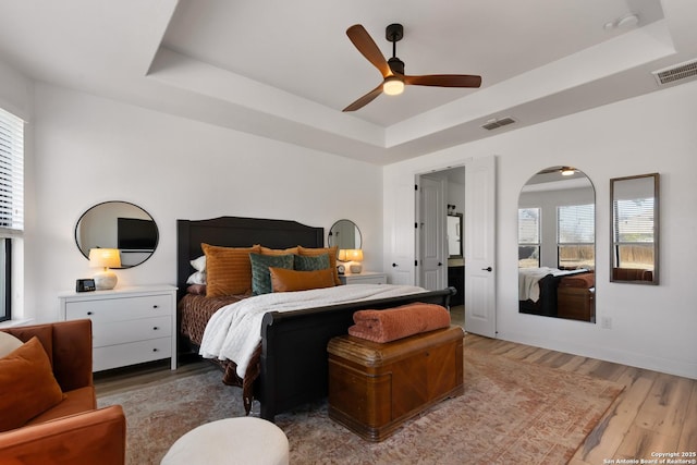 bedroom featuring visible vents, multiple windows, and a tray ceiling