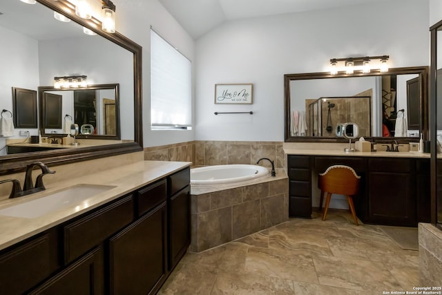 full bathroom with a stall shower, a sink, a garden tub, vaulted ceiling, and two vanities