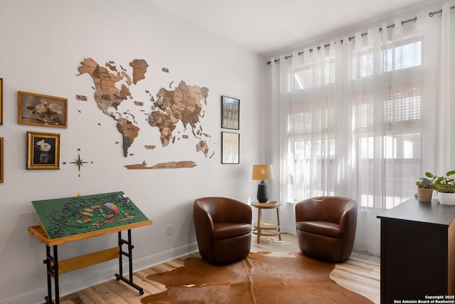 sitting room with plenty of natural light, baseboards, and wood finished floors