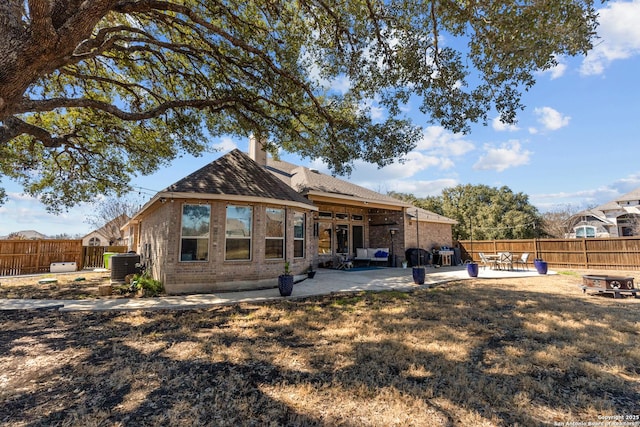 back of house featuring brick siding, a fenced backyard, cooling unit, and a patio