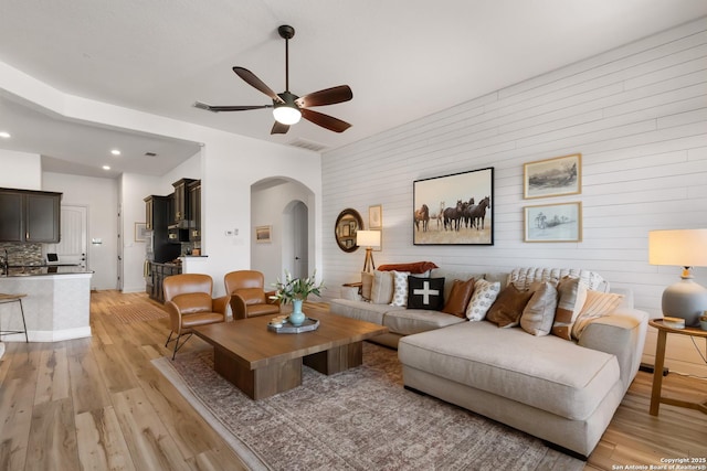 living room with visible vents, arched walkways, ceiling fan, light wood-style flooring, and recessed lighting