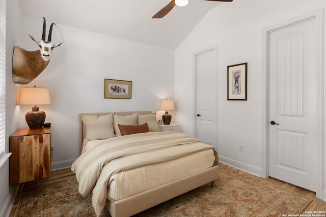 bedroom featuring lofted ceiling, baseboards, and wood finished floors