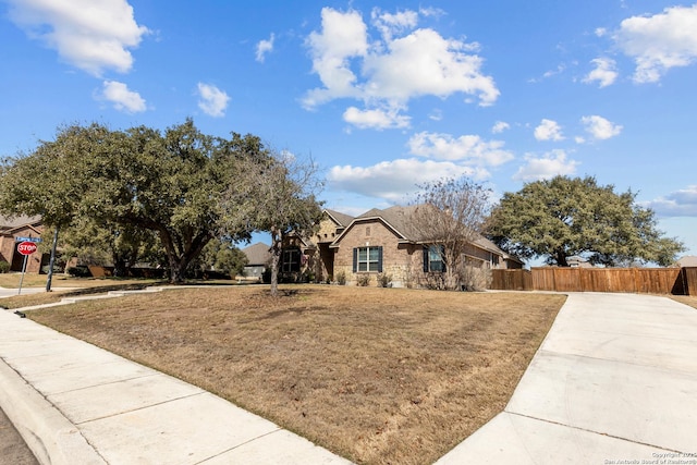 view of front of house featuring stone siding, a front lawn, and fence