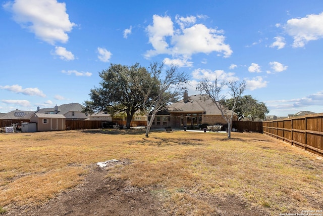 view of yard featuring a fenced backyard, a storage unit, and an outdoor structure